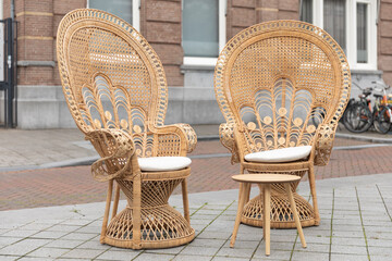 Two rattan wicker chairs in peacock shape and boho, hippie, eclectic home decor style standing...