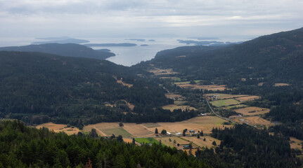 Fototapeta na wymiar Aerial View of Salt Spring Island and farms from the top of Mt. Maxwell. Cloudy Summer Morning. Gulf Islands, British Columbia, Canada. Canadian Nature Background
