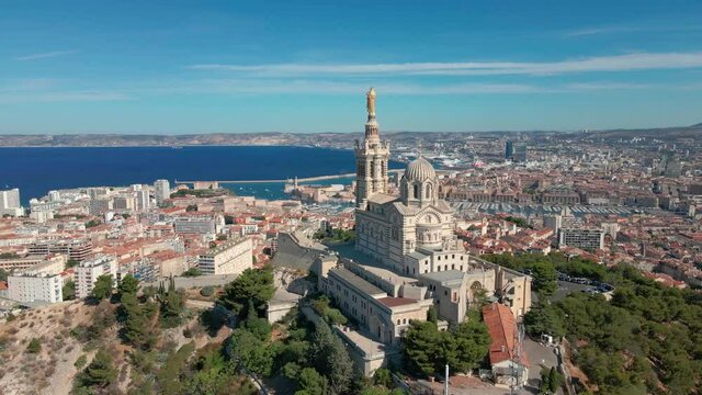 Marseille, France aerial video with view of basilica Notre Dame de la Garde, old city center and port and blue Mediterranean sea coast, warm sunny day. Summer holiday vacation tourism destination.