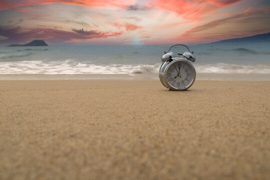 analog clock marking the time of the tides in the sand on the shore of the beach with time copy