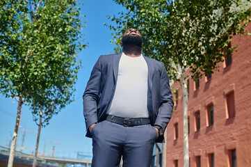 A dark-skinned man in a suit standing in the street