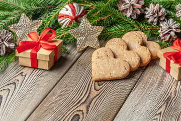 festive christmas and new year background with copy space, fir branches, сhristmas decorations, pine cones, gingerbread cookies and gifts on a vintage wooden table