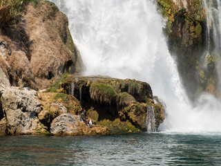 A fisherman next to a waterfall