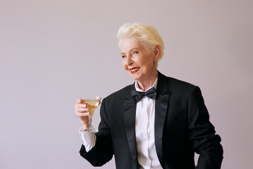 stylish mature sommelier senior woman in tuxedo with glass of sparkling wine. Fun, party, style, lifestyle, alcohol, celebration concept