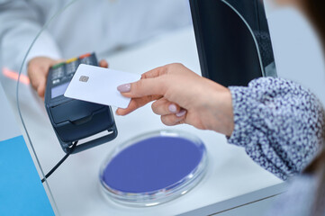 Womans hand bringing credit card to pos terminal