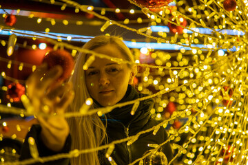 woman with blonde hair on the street on the background lights Christmas decorations