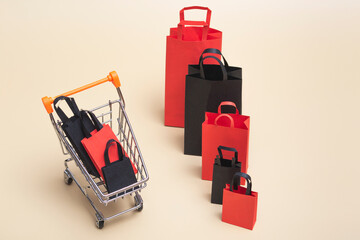 Obraz premium Black friday concept, mockup of paper black and red shopping bags with trolley on colored background. Black Friday sale.