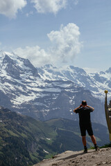 Backpacker hiker observing panoramic view on Eiger, Monch and Jungfraujoch and green Alps around...