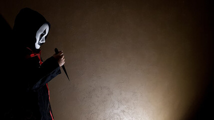 the devil holds a dagger in his hands. a demon with a knife on a dark background. background fear and horror