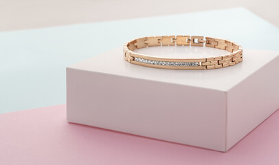 Focus on diamonds on golden bracelet on pastel colors background with copy space - obrazy, fototapety, plakaty