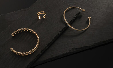 Chain shape and golden with diamonds bracelets and ring on dark stone plates with copy space