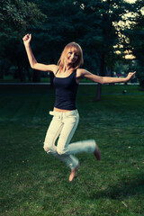 Fototapeta na wymiar Slim blonde jumping on green grass