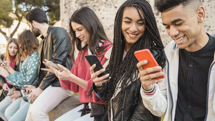 Group of friends gaming outdoor with their smartphones - Cheerful young people using cellphone outdoors. Tech concept. © Lomb