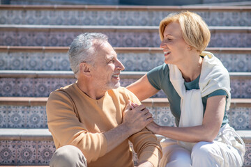 Happy middle-aged couple seated on the steps