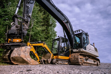 Small and big excavators at a construction site low angle view
