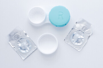 The lens container and two sealed lenses lie in the center on a white background. top view, flat lay, copy space, isolate