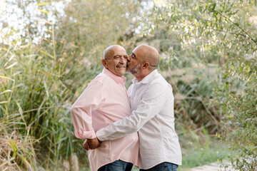 Lovely middle-aged gay couple looking happy while enjoying a date together in a park. LGBT couple concept.