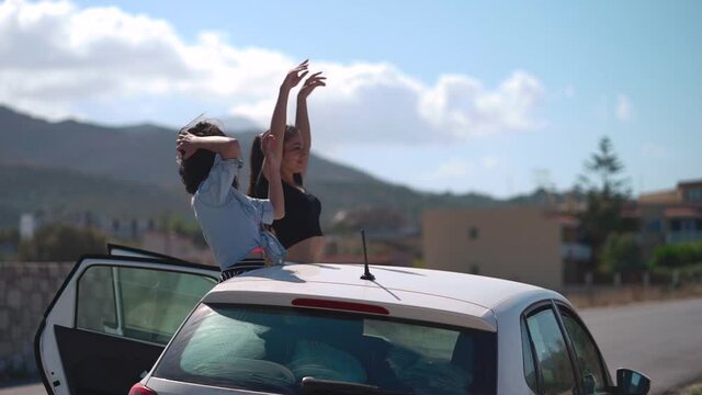 Two friends running to a car at the beach. Best friends spend summer time together. The girls are happy and enjoy life. The road by car to the sea. Friendship and love forever. The beauty of Greece.