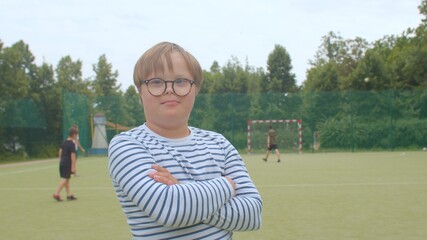 Portrait of a smiling boy on football field. Children with Down syndrome. A disease resulting from...