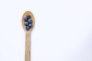 Flat lay of recycled spoon and juicy, fresh blueberries on color table. Space for text. Isolated ripe sweet bilberry fruits in eco spoon on white background. Copy Space. Healthy raw vegetarian food 