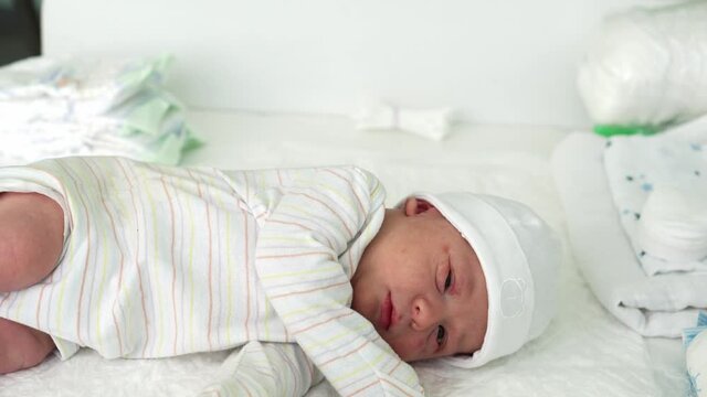 Awake Newborn Baby Face Portrait Acne Allergic Irritations Early Days Sneeze On White Background. Child Start Minutes Of Life on Hat. Infants, Childbirth, First Moments Of Borning, Beginning Concept