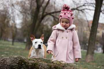 Cute baby girl with her dog in a public park