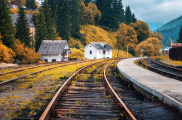 Railway station and small white house in mountain village in autumn in Europe. Rural railroad in...