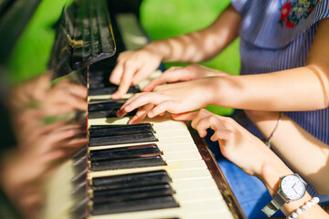 hands of a young pianist teacher teaches a girl student to play the piano, the concept of music education, love of art.