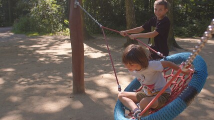 Children are actively playing on the playground in the park. Bully boy showing noncompliant...