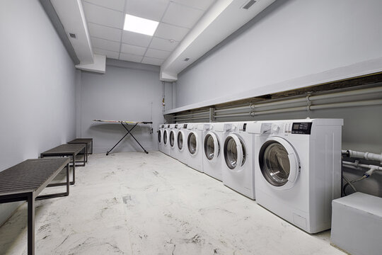 Row of washing machines and an ironing board in a public laundry room