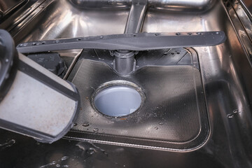 A hand taking out dishwasher filter to clean it, dis washer cleaning concept, kitchen home...