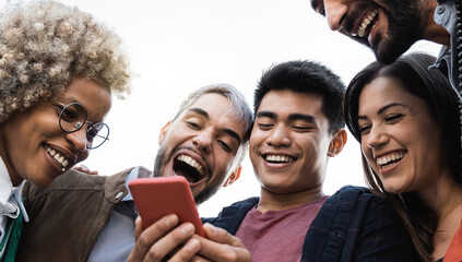 Obraz premium Young diverse friends having fun using mobile phone outdoor in the city - Main focus on asian man face