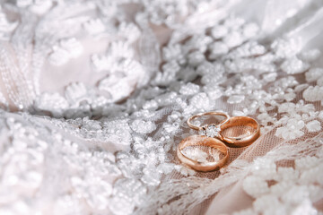 Obraz na płótnie Canvas wedding gold rings with diamonds lie on the bride's dress