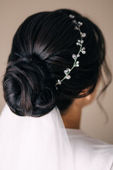 Naklejka premium Hairstyle for a wedding with a veil. The bride stands with her back to the camera. Braiding hair diadem ornaments. Preparation for the ceremony. Morning of the bride.