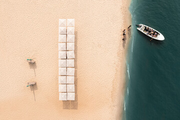 Motorboat near sandy coast with beach umbrellas, aerial view. Summer vacation