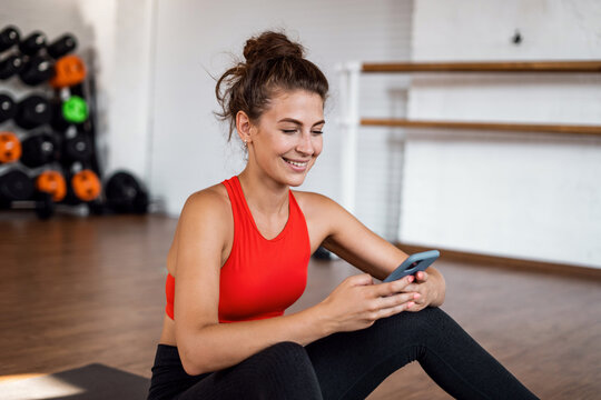 Uses the phone fitness app. Comfortable tight-fitting clothing for training. Slim figure cardio classes. An aerobics coach does exercises. A sporty woman and a healthy lifestyle.