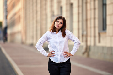 Young woman makes grimace while stands outdoors at daytime.
