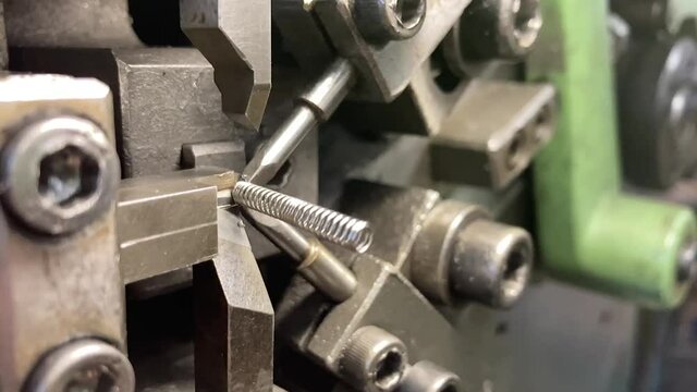 Spring winding on the machine. Manufacturing of a spring in production.Slow motion video. 