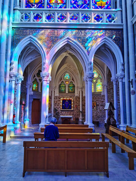 Old woman praying in the beautiful interior of the basilica of Pontmain.