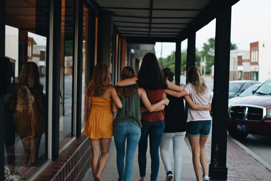 Back View Of A Group Of Female Friends Hugging And Walking Outdoors