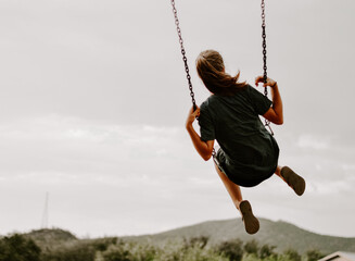 Back view of a female in the air on a swing