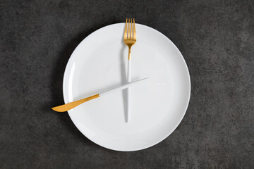 Concept of intermittent fasting, diet. Fork and knife crossed on plate. Flat lay, top view, copy space