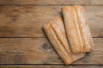 Delicious ciabattas on wooden table, flat lay. Space for text
