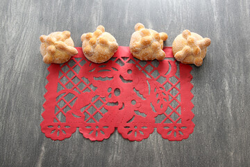 Papel picado tablecloth on wooden table as Mexican Day of the Dead decoration with delicious, fluffy and sugary bread of the dead
