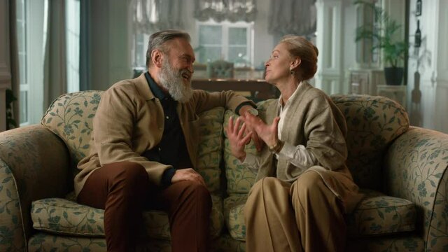Cheerful elderly couple talking at luxury home. Tender relationship concept.