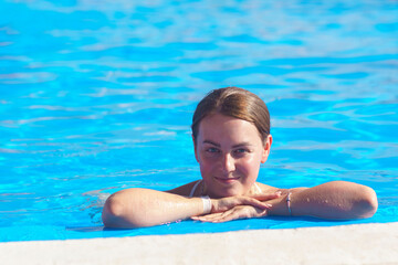 Portrait of a young woman in sunglasses in the swimming pool.Pretty girl resting on the edge of a swimming pool.Sexy girl relaxing in water on hot sunny day.