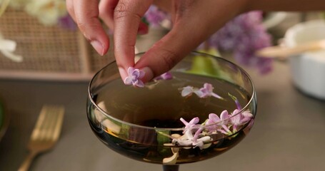 Hand of a woman who is putting a flower in a cocktail