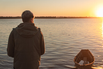 Fototapeta premium Young boy appreciating the sunset on the sea shore.