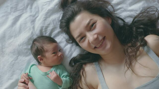 Asian Mother and her baby daughter are making selfie or video call to father in bed , Family , Home safety , parenthood , technology concept