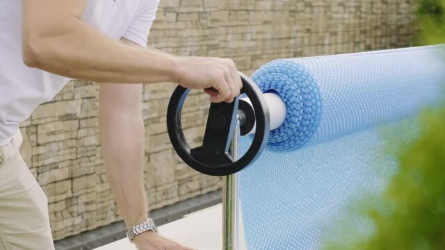 A man collects bubble wrap for the pool. Home pool protection concept

